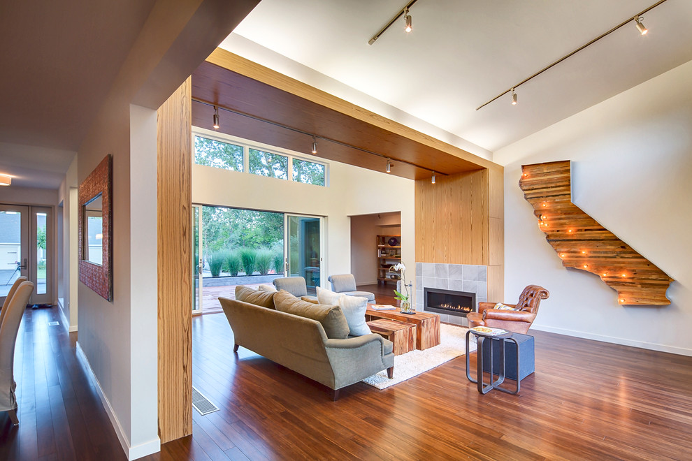 Idee per un ampio soggiorno moderno con pareti bianche, pavimento in bambù e cornice del camino piastrellata
