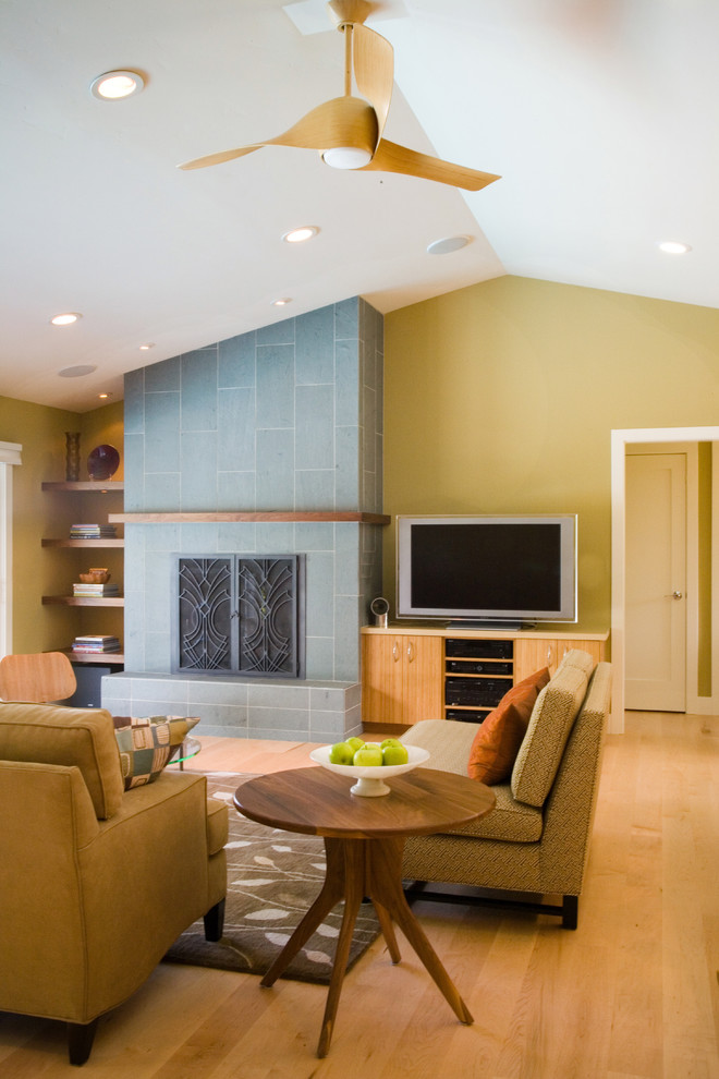 На фото: гостиная комната:: освещение в стиле ретро с желтыми стенами, стандартным камином и отдельно стоящим телевизором с