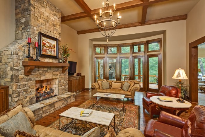 Example of a large classic open concept medium tone wood floor living room design in Other with beige walls, a standard fireplace, a stone fireplace and a wall-mounted tv