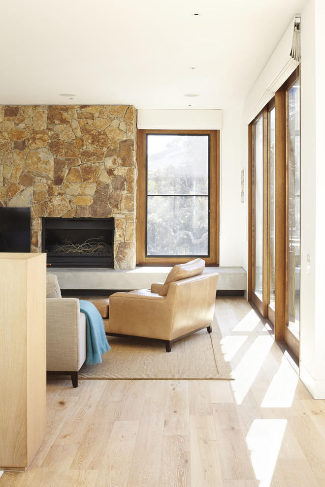 Mittelgroßes, Offenes Modernes Wohnzimmer mit weißer Wandfarbe, hellem Holzboden, Kamin, Kaminumrandung aus Stein und TV-Wand in Melbourne
