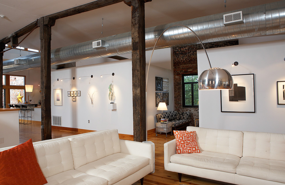 Foto på ett industriellt vardagsrum, med vita väggar och ljust trägolv