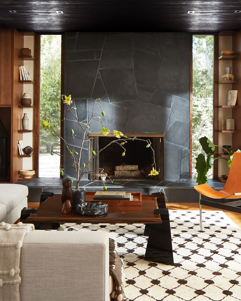 Idées déco pour un salon contemporain avec un mur blanc, un sol en bois brun, une cheminée standard, un manteau de cheminée en pierre et un sol marron.