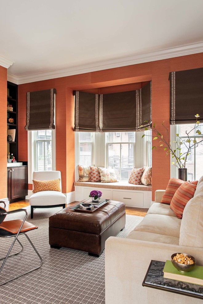 На фото: двухуровневая гостиная комната среднего размера в стиле неоклассика (современная классика) с домашним баром, оранжевыми стенами, паркетным полом среднего тона и эркером без камина, телевизора с