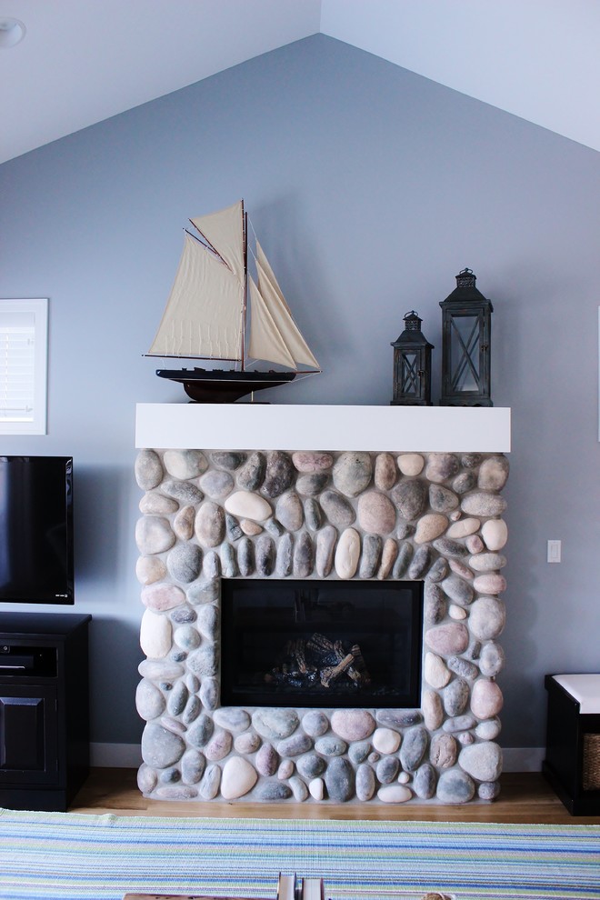 Photo of a nautical living room in Grand Rapids with medium hardwood flooring, a standard fireplace and a stone fireplace surround.