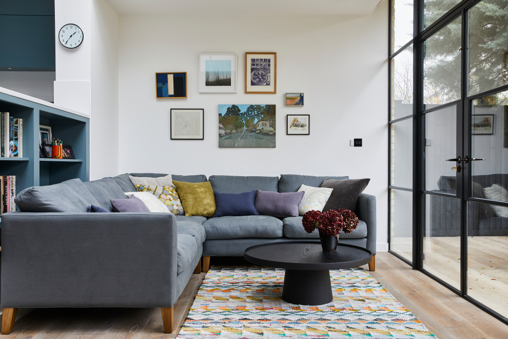 Immagine di un soggiorno design aperto con pareti bianche, pavimento in legno massello medio e pavimento marrone