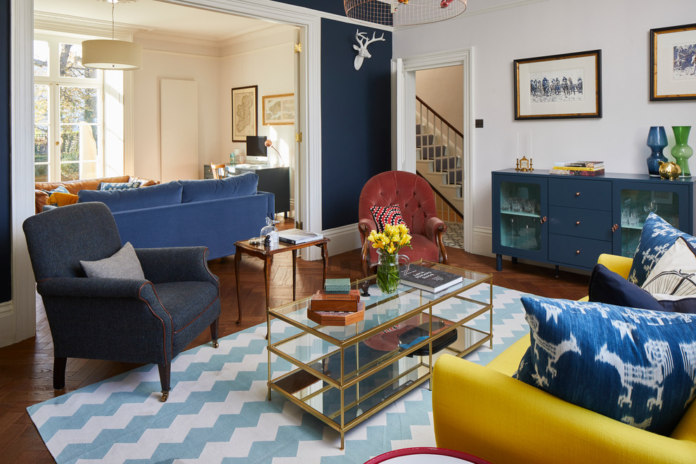 Foto di un grande soggiorno vittoriano chiuso con pareti blu, pavimento in legno massello medio, cornice del camino in pietra e pavimento marrone