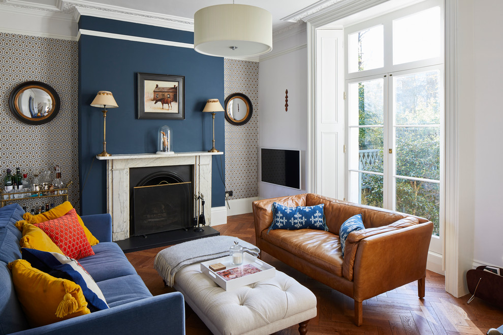 ロンドンにあるお手頃価格の広いヴィクトリアン調のおしゃれな独立型リビング (青い壁、無垢フローリング、石材の暖炉まわり、茶色い床) の写真