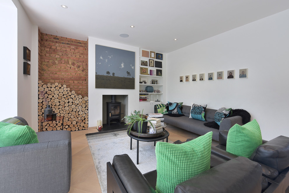 Repräsentatives, Abgetrenntes Modernes Wohnzimmer mit weißer Wandfarbe, hellem Holzboden, Kaminofen, verputzter Kaminumrandung und beigem Boden in London