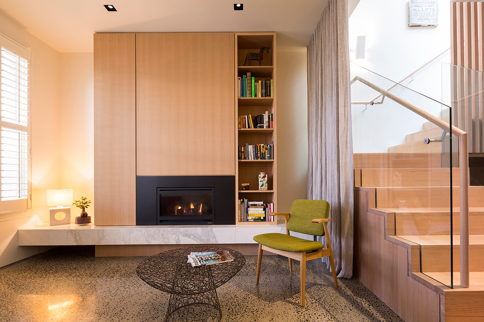 Идея дизайна: открытая гостиная комната среднего размера в современном стиле с с книжными шкафами и полками, белыми стенами, бетонным полом, стандартным камином и фасадом камина из металла