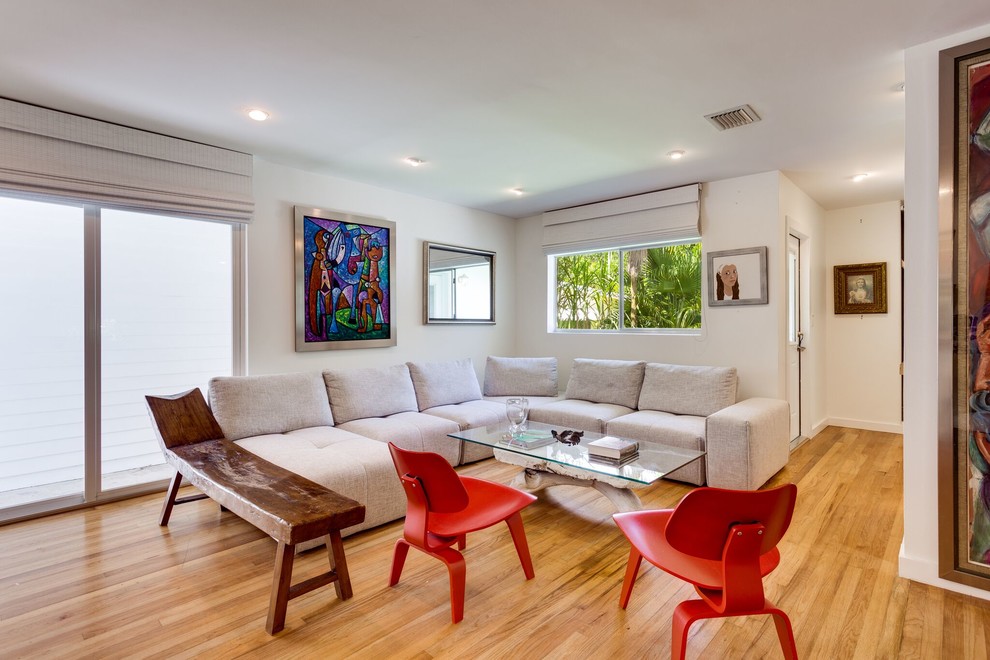 Small contemporary formal open plan living room in Miami with white walls, light hardwood flooring and brown floors.