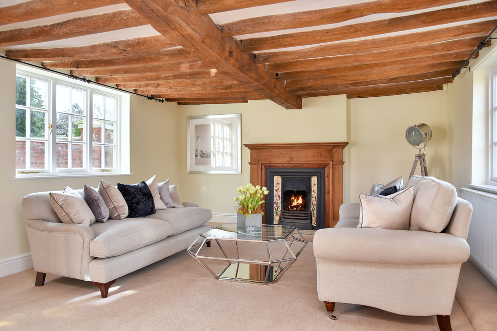 Photo of a medium sized farmhouse formal enclosed living room in Other with yellow walls, carpet, a standard fireplace, a metal fireplace surround and beige floors.