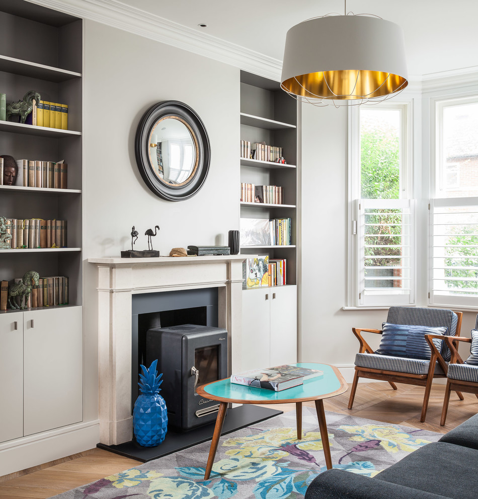 Modernes Wohnzimmer mit grauer Wandfarbe, hellem Holzboden, Kaminofen, Kaminumrandung aus Metall und braunem Boden in London