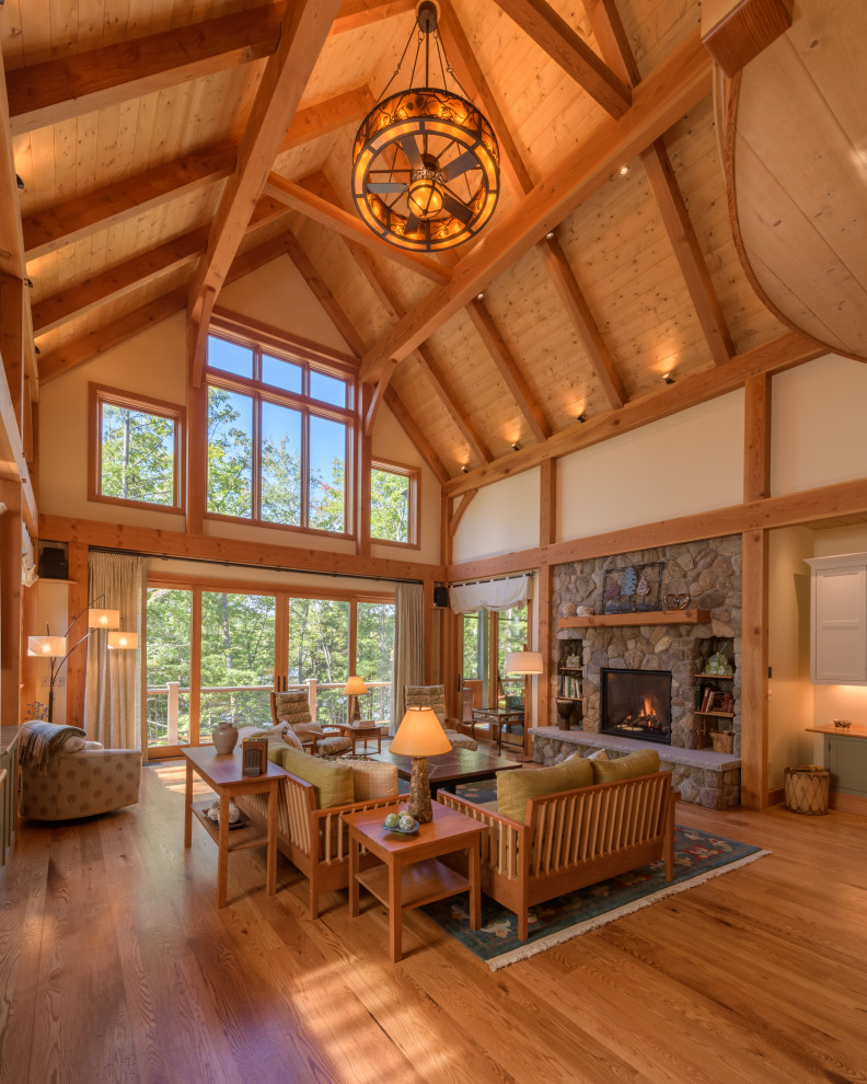 Photo of an expansive rustic mezzanine living room in Other with medium hardwood flooring, a standard fireplace and a stone fireplace surround.