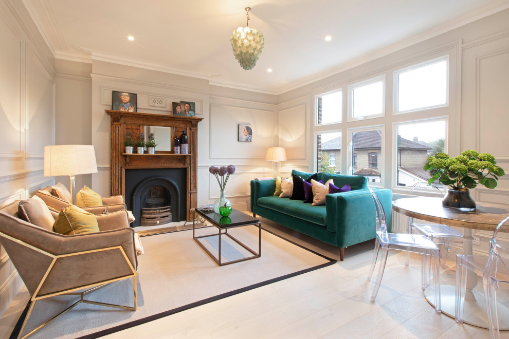 This is an example of a classic formal enclosed living room in London with white walls, light hardwood flooring, a standard fireplace, a wooden fireplace surround, no tv, beige floors and panelled walls.