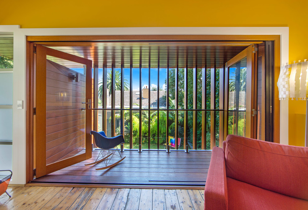 Foto de salón abierto actual pequeño con paredes amarillas y suelo de madera en tonos medios