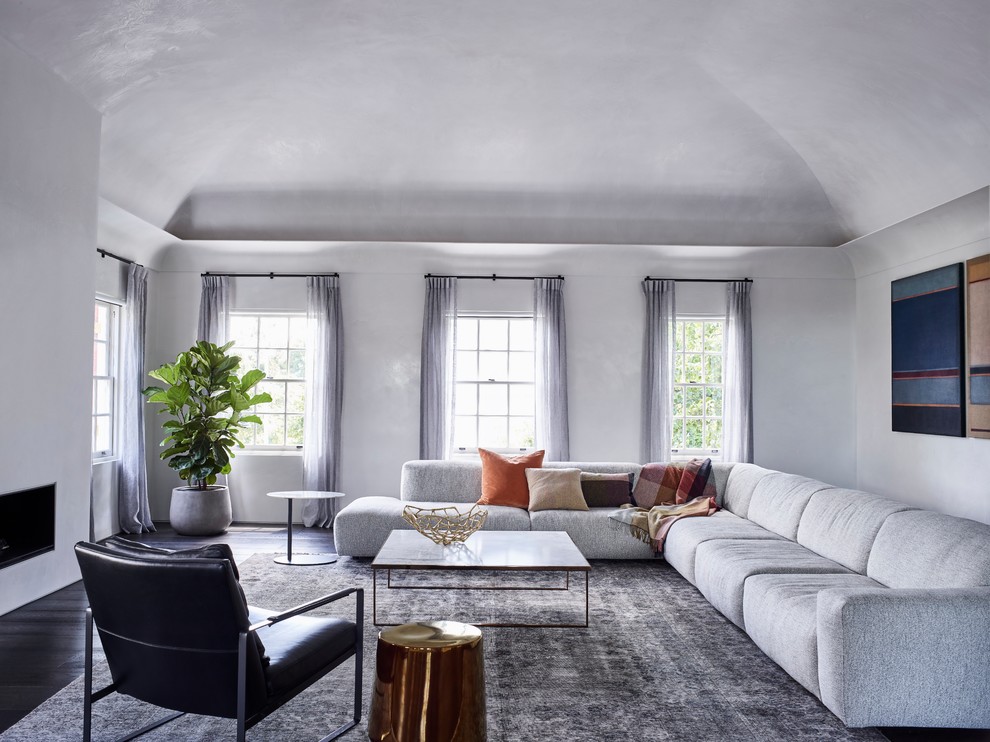 Idee per un soggiorno minimal con pareti grigie, parquet scuro, camino classico e cornice del camino in cemento