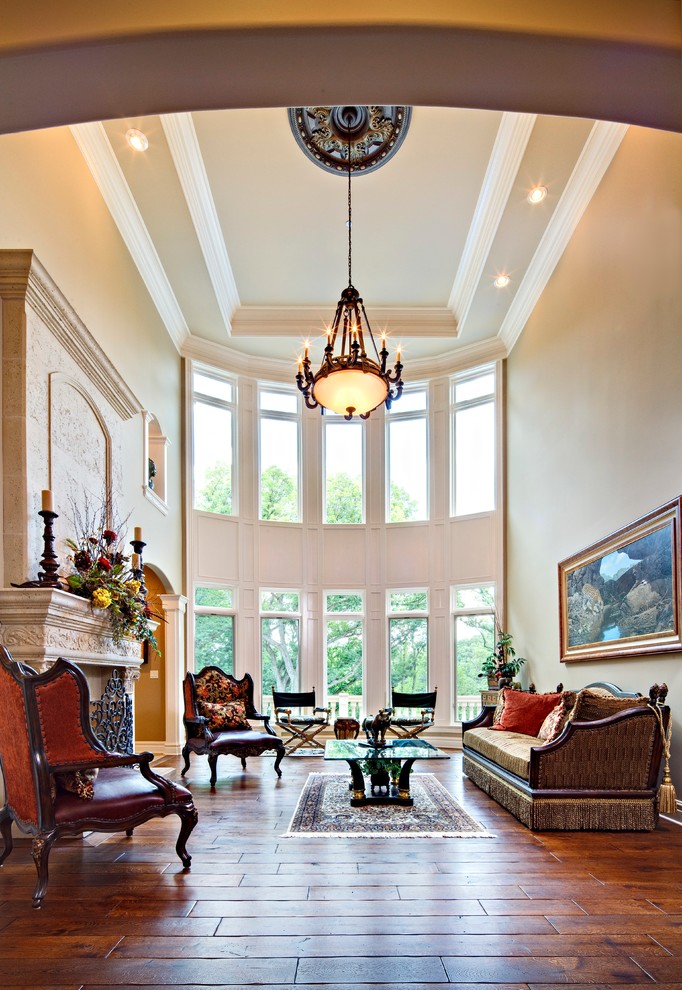 Пример оригинального дизайна: большая парадная, открытая гостиная комната в классическом стиле с бежевыми стенами, паркетным полом среднего тона, стандартным камином, фасадом камина из камня и коричневым полом без телевизора