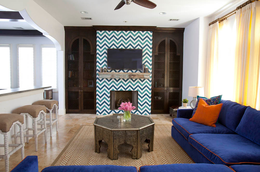 Свежая идея для дизайна: гостиная комната в средиземноморском стиле с белыми стенами, стандартным камином, фасадом камина из плитки и синим диваном - отличное фото интерьера