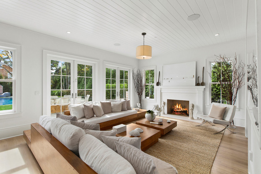 Offenes Maritimes Wohnzimmer mit weißer Wandfarbe, hellem Holzboden und Kamin in Los Angeles