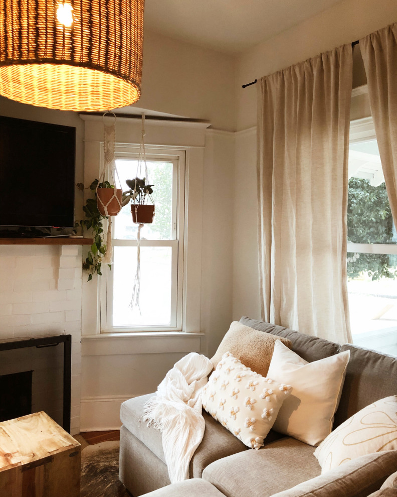 Kleines, Offenes Eklektisches Wohnzimmer mit weißer Wandfarbe, braunem Holzboden, Kamin, Kaminumrandung aus Backstein, freistehendem TV und braunem Boden in Portland