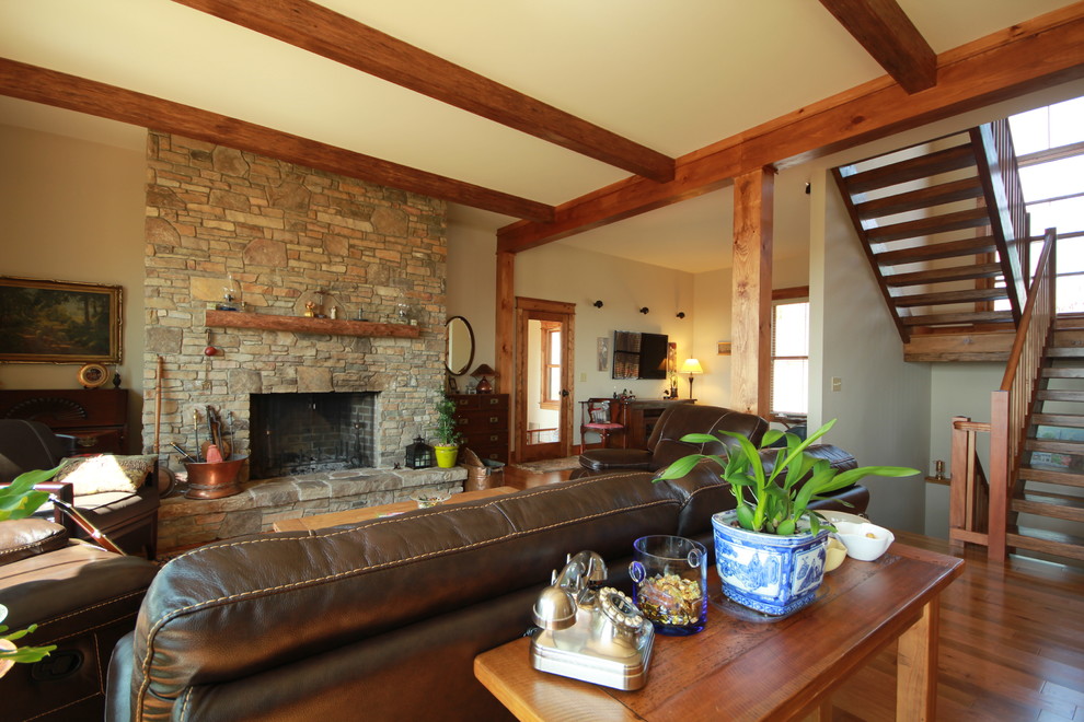 Ejemplo de salón abierto de estilo de casa de campo de tamaño medio con paredes beige, suelo de madera en tonos medios, todas las chimeneas y marco de chimenea de piedra