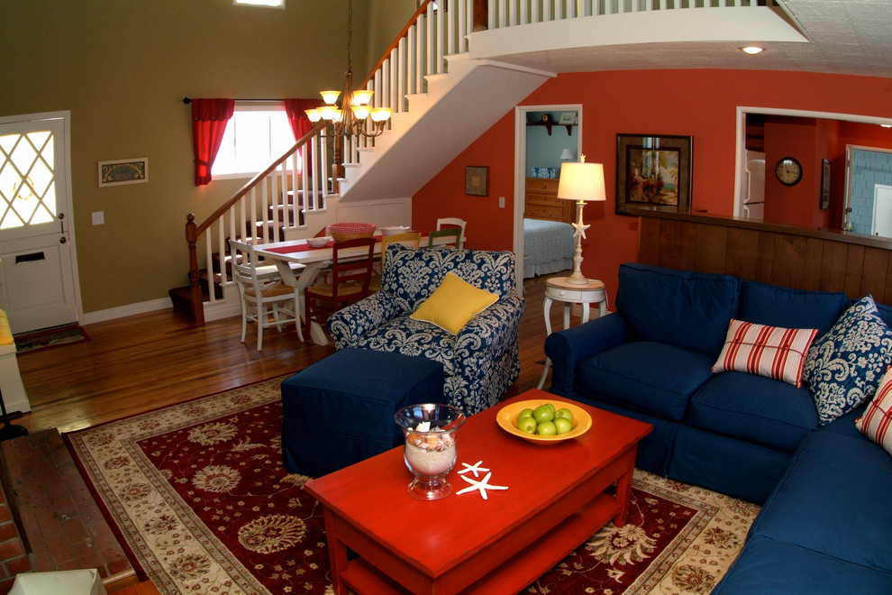 На фото: парадная, открытая гостиная комната среднего размера в морском стиле с красными стенами, темным паркетным полом, стандартным камином, фасадом камина из кирпича и коричневым полом без телевизора
