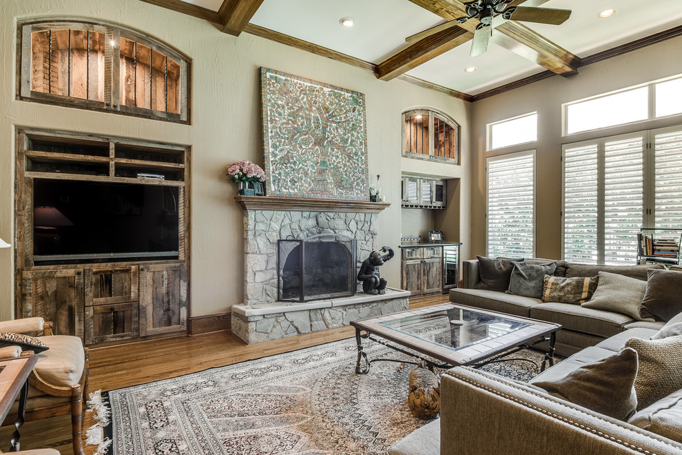 Inspiration for a large transitional formal and enclosed medium tone wood floor and brown floor living room remodel in Dallas with beige walls, a standard fireplace, a stone fireplace and a wall-mounted tv
