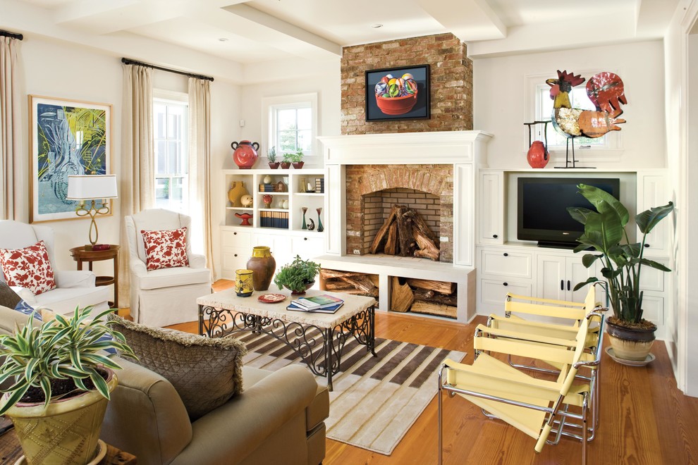 Exemple d'un salon chic avec une salle de réception, un mur blanc, un sol en bois brun, une cheminée standard, un manteau de cheminée en brique et un téléviseur encastré.