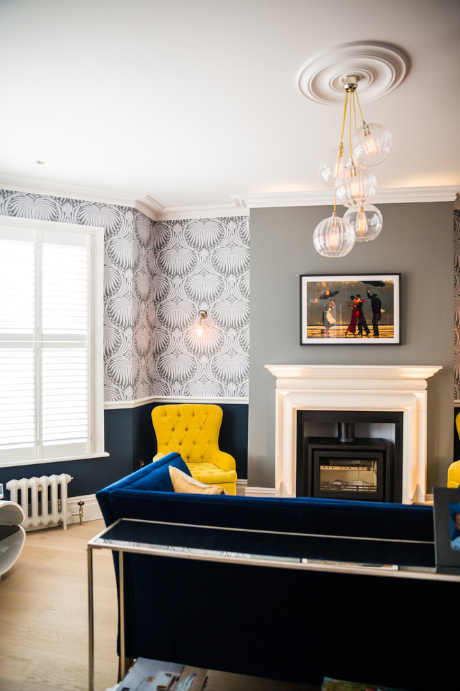 Пример оригинального дизайна: гостиная комната в современном стиле с серыми стенами, светлым паркетным полом, печью-буржуйкой, фасадом камина из металла, бежевым полом и синим диваном