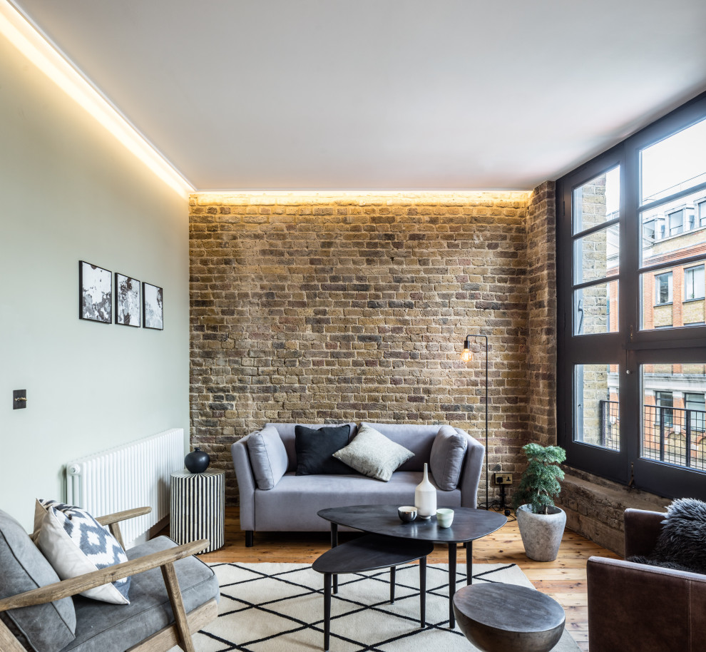 Fernseherloses, Offenes Industrial Wohnzimmer ohne Kamin mit braunem Holzboden in London