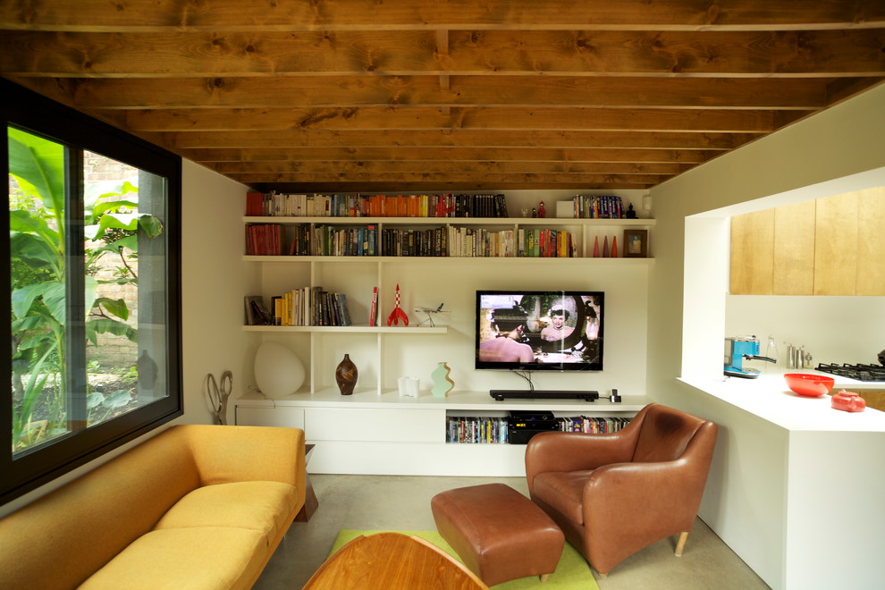Пример оригинального дизайна: маленькая открытая гостиная комната в стиле модернизм с белыми стенами, бетонным полом, телевизором на стене и серым полом без камина для на участке и в саду