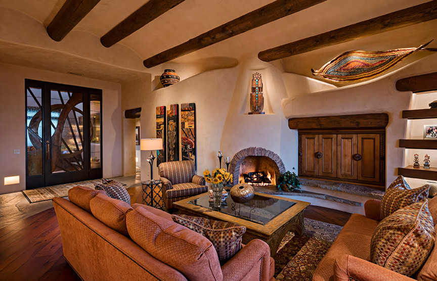 Mediterranes Wohnzimmer mit braunem Holzboden, Kamin, verputzter Kaminumrandung und verstecktem TV in Phoenix