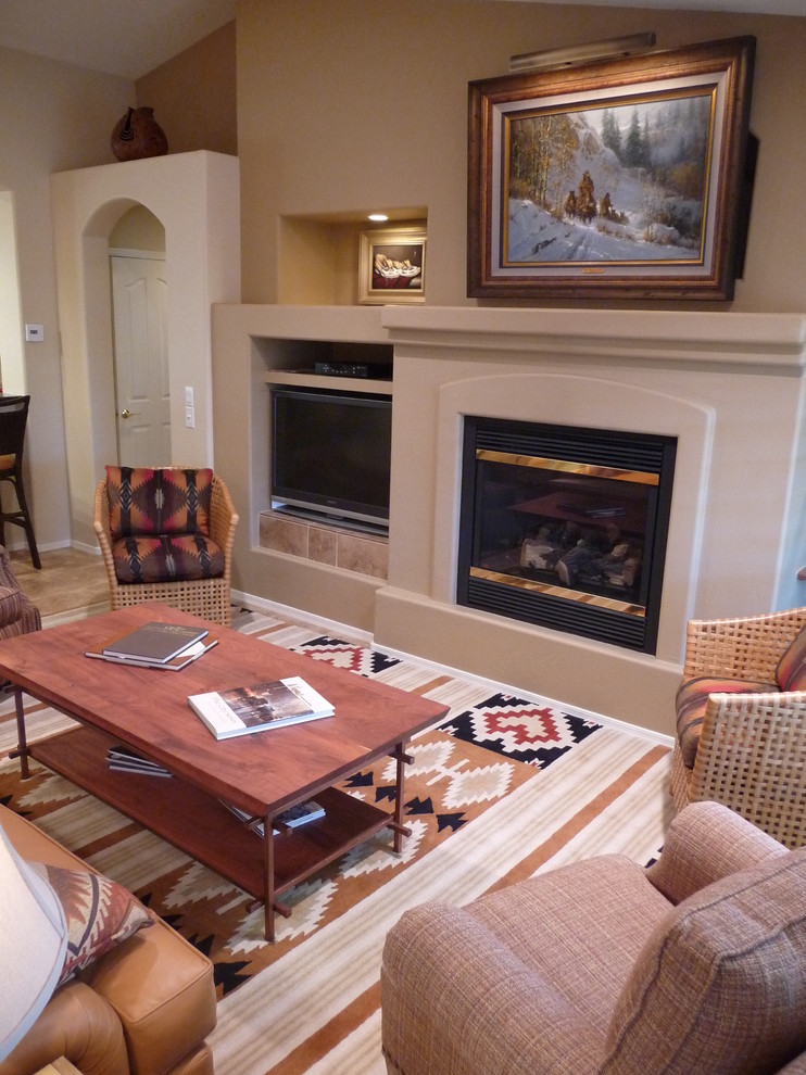 Cette image montre un grand salon sud-ouest américain ouvert avec un mur beige, un sol en carrelage de porcelaine, une cheminée standard, un téléviseur encastré, un manteau de cheminée en plâtre et un sol beige.
