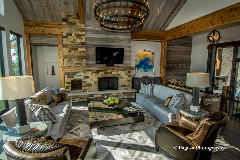Example of a large southwest open concept dark wood floor and brown floor living room design in Denver with beige walls, a standard fireplace, a stone fireplace and a wall-mounted tv