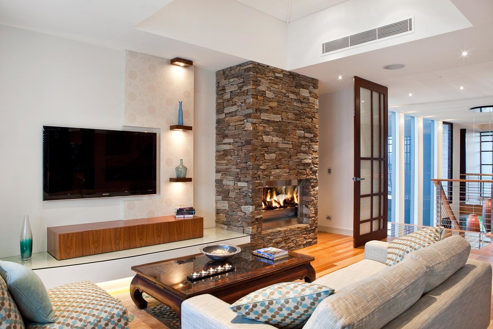 Свежая идея для дизайна: изолированная гостиная комната в морском стиле с белыми стенами, паркетным полом среднего тона, стандартным камином, фасадом камина из камня и телевизором на стене - отличное фото интерьера