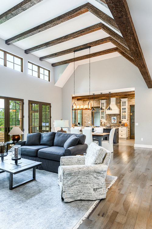 Cottage open concept light wood floor, brown floor and exposed beam living room photo in Other with gray walls