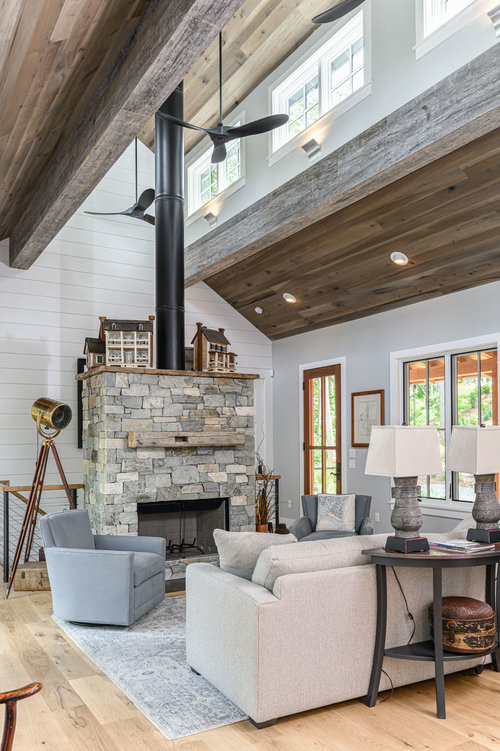Design ideas for a rustic living room in Other with white walls, light hardwood flooring, a standard fireplace, a stone fireplace surround, brown floors, a vaulted ceiling and tongue and groove walls.