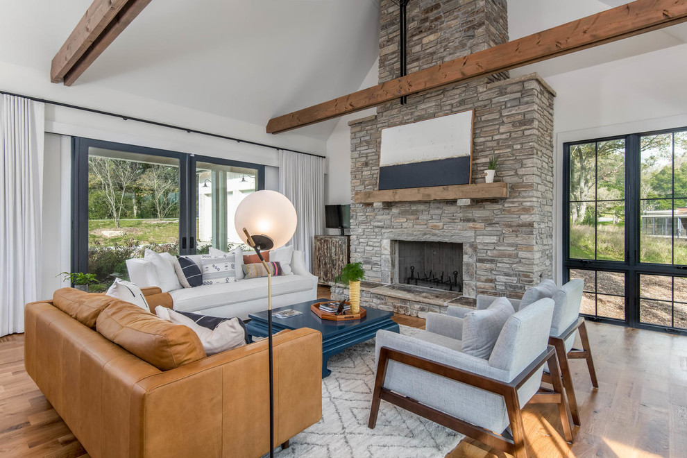 Farmhouse open plan living room in Other with white walls, medium hardwood flooring, a standard fireplace, a stone fireplace surround and brown floors.