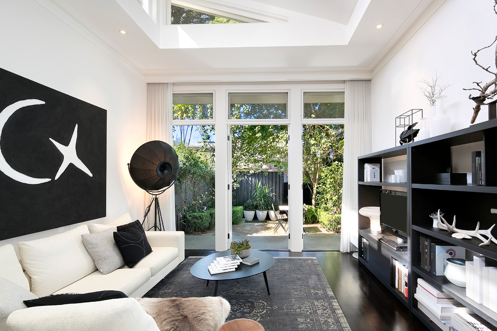 Exempel på ett klassiskt allrum med öppen planlösning, med vita väggar, mörkt trägolv, en fristående TV och brunt golv