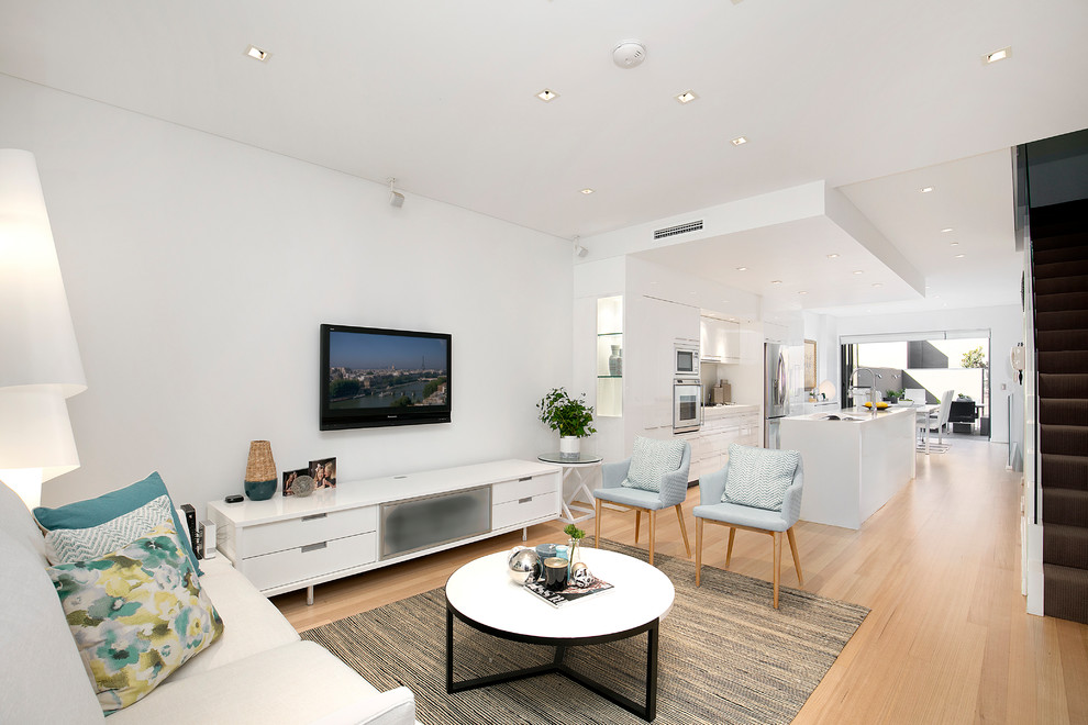 Exempel på ett modernt vardagsrum, med vita väggar, ljust trägolv och en väggmonterad TV