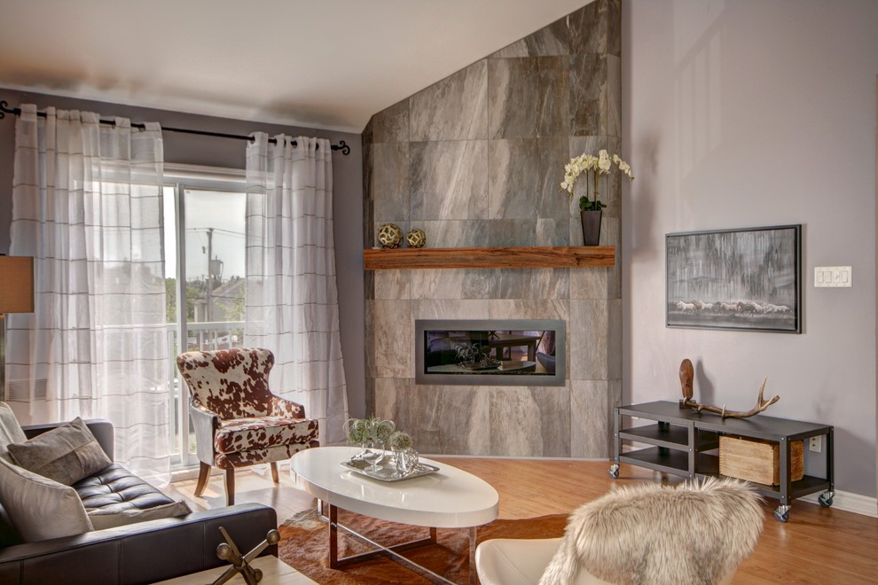 Aménagement d'un salon scandinave de taille moyenne et ouvert avec un mur gris, parquet clair, une cheminée d'angle, un manteau de cheminée en carrelage et aucun téléviseur.