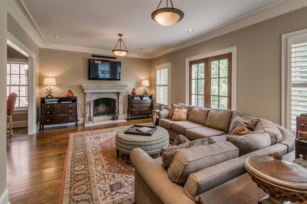 Example of a large classic open concept medium tone wood floor and brown floor living room design in Nashville with beige walls, a standard fireplace, a stone fireplace and a wall-mounted tv