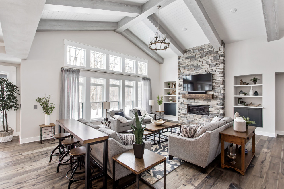 Inspiration for a country open concept dark wood floor, brown floor, exposed beam, shiplap ceiling and vaulted ceiling living room remodel in New York with gray walls, a ribbon fireplace, a stacked stone fireplace and a wall-mounted tv