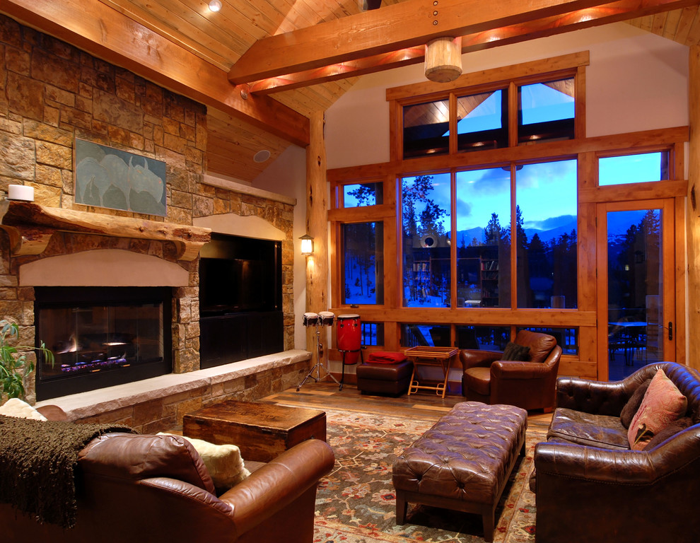 Inspiration for a mid-sized rustic open concept medium tone wood floor living room remodel in Denver with beige walls, a standard fireplace, a stone fireplace and a media wall