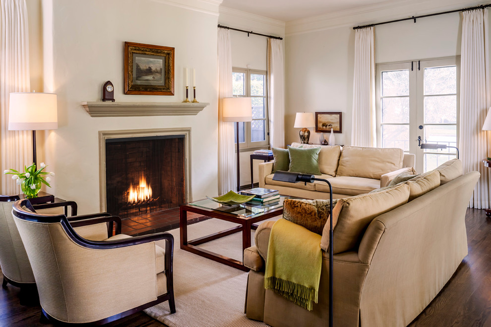 This is an example of a medium sized traditional formal enclosed living room in Los Angeles with beige walls, dark hardwood flooring, a standard fireplace and a plastered fireplace surround.