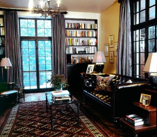 Ejemplo de biblioteca en casa tradicional con paredes amarillas, suelo de madera en tonos medios, todas las chimeneas y marco de chimenea de piedra