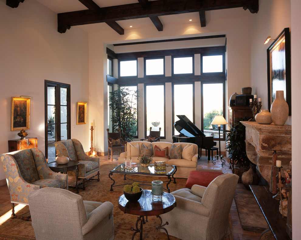 На фото: большая парадная, изолированная гостиная комната в средиземноморском стиле с бежевыми стенами, полом из терракотовой плитки, стандартным камином и фасадом камина из камня без телевизора