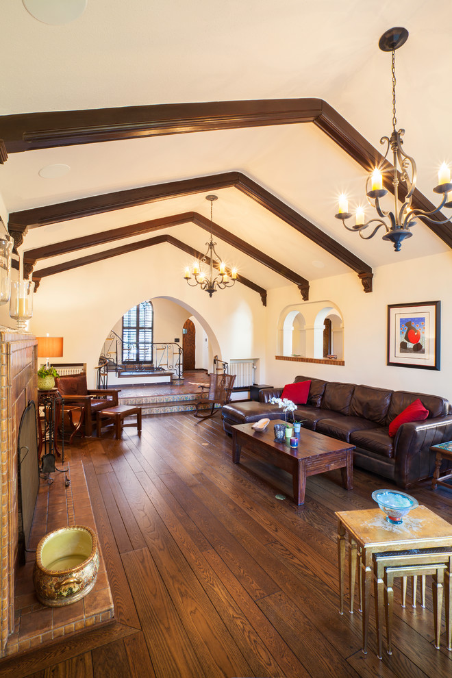 This is an example of a large mediterranean open plan living room in Seattle with a tiled fireplace surround, medium hardwood flooring, a standard fireplace, no tv, beige walls and brown floors.