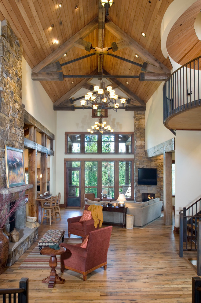 This is an example of a large rustic open plan living room in Other with white walls, medium hardwood flooring, a standard fireplace and a stone fireplace surround.