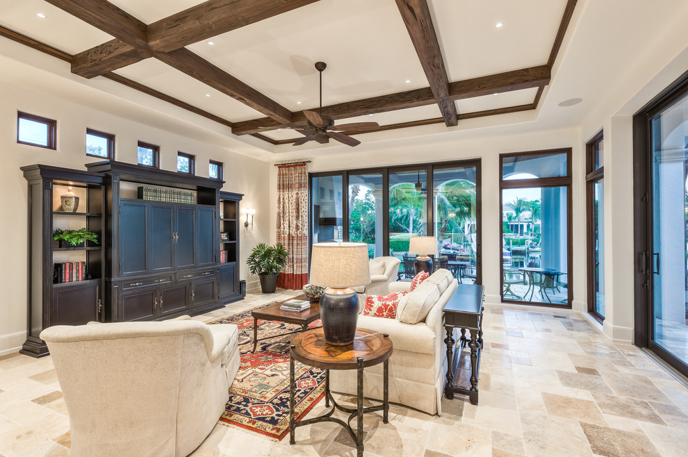 Example of a large tuscan enclosed travertine floor and brown floor living room design in Miami with white walls, no fireplace and a concealed tv